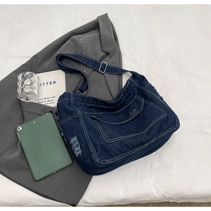 Primo piano della borsa in denim blu lavato con dettagli usurati e tracolla regolabile