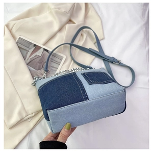 Detail of blue denim patchwork bucket bag with silver metal chain and shoulder strap