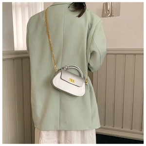 Detail of silver metallic crossbody bag with gold chain strap on minimalist outfit