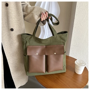 Detail of green canvas tote bag featuring dual brown contrast front pockets with magnetic closures