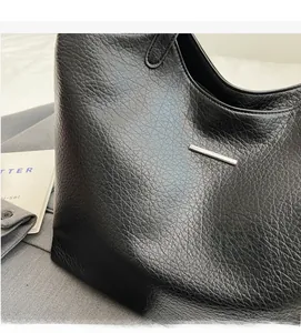 Close-up of black lychee grain leather tote bag with silver metal bar hardware detail