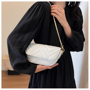 Detail of white quilted leather bag with V-shaped stitching and gold chain strap