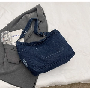 Dettaglio borsa a tracolla in denim blu scuro con cuciture a contrasto ed effetti usurati
