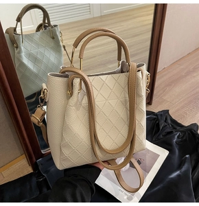 Detailed view of beige quilted leather bucket bag with contrasting brown handles