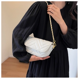 Detail of white quilted crossbody bag featuring V-shaped stitching and gold chain strap