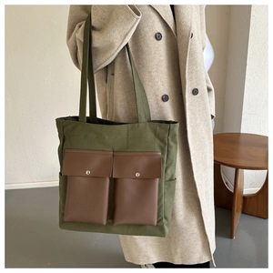 Detail of army green canvas tote bag with brown flap pockets on beige coat