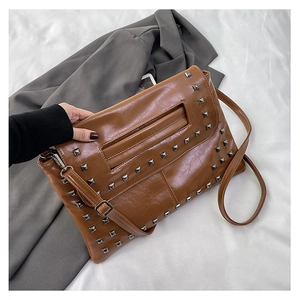 Dettaglio borsa in ecopelle caramello con borchie quadrate argentate e cinturino a mano