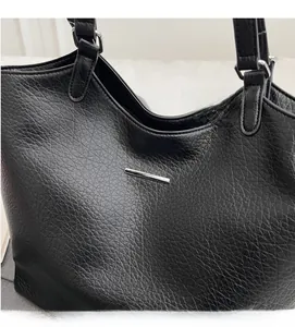 Close-up of black pebble grain leather tote bag with minimalist silver metal bar detail