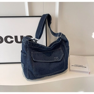 Dettaglio borsa a tracolla in denim blu scuro con cuciture a contrasto e tracolla regolabile