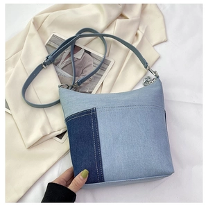Close-up of contrast denim bucket bag with silver chain links and adjustable strap