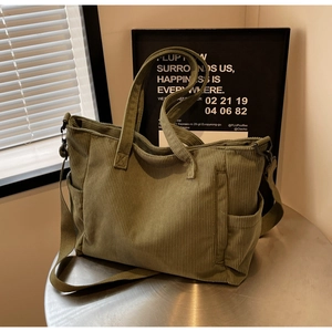 Detailed side view of an olive green corduroy tote bag with adjustable shoulder strap
