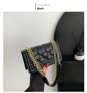 Detail of black quilted shoulder bag with luxury gold chain and stitching texture