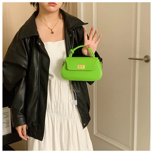 Detail of lime green leather mini handbag featuring a gold twist lock and top handle