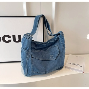 Vista dettagliata della borsa in denim con tessuto lavato blu e tasca anteriore a patta