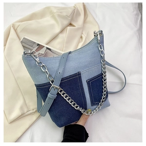 Detailed close-up of patchwork denim shoulder bag with silver chain and adjustable strap