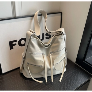 Detail of beige corduroy backpack showing heart-shaped zipper pockets and fabric texture