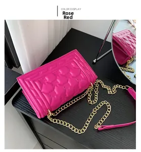 Detail view of a rose red quilted chain shoulder bag with elegant gold metal strap