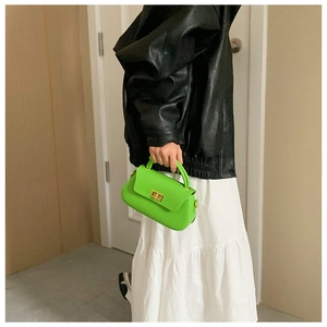 Neon green crossbody bag with gold twist lock shown on model with black outfit
