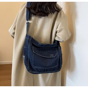 Dettaglio della borsa tote in denim blu con tasca a patta sfrangiata su un trench