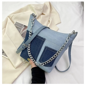 Detail of color-block denim bucket bag with silver chain strap and multiple pockets
