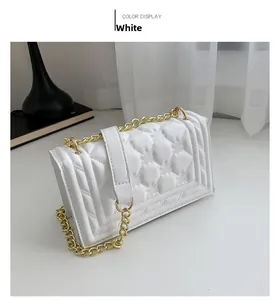 Detailed close-up of white quilted handbag with golden chain strap and geometric texture