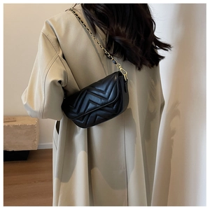 Detail showing the black V-quilted texture and metal chain strap of the crossbody bag