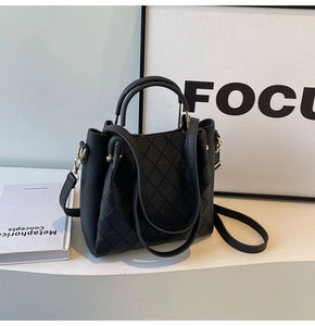 Close-up of black quilted bucket bag with pebble leather texture and gold hardware detail