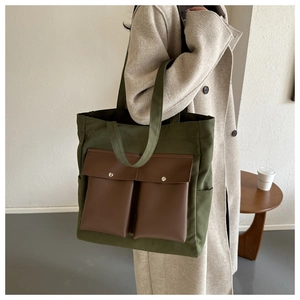 Detail view of large canvas tote bag with military green fabric and brown leather pockets