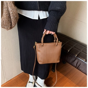 Detailed view of brown pleated bucket bag with vertical texture and dual handles
