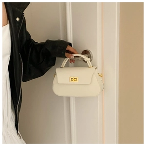 Detailed close-up of cream mini handbag with gold rotary lock and woven handle detail