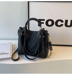 Close-up of black quilted bucket bag with gold hardware and lychee grain texture detail