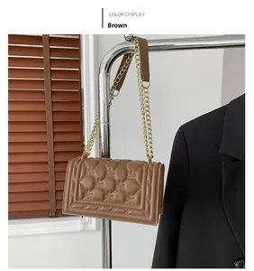 Detail of a brown quilted square handbag with diamond patterns and golden chain strap