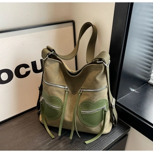 Detail of army green canvas tote bag featuring unique heart-shaped zipper pockets and strap