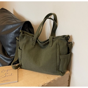 Detail view of dark green corduroy tote bag showing texture and adjustable shoulder strap