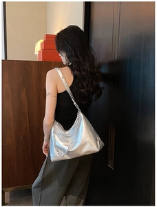 Detail of silver metallic tote bag with chain strap and soft pleated texture on leather