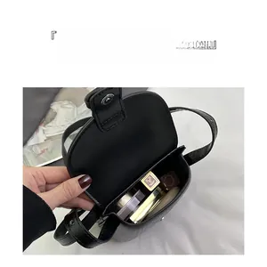Internal view of a small black leather crossbody bag showing capacity for cosmetics