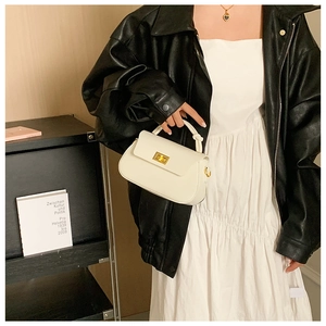 Detail of ivory fashion handbag with gold twist clasp and decorative knotted handle