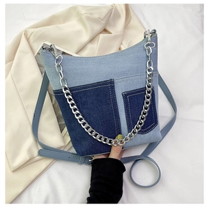 Detail of blue denim bucket bag featuring patchwork design and chunky silver metal chain