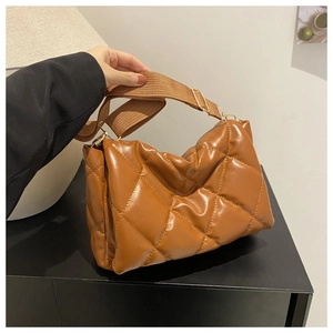 Dettaglio di una borsa a tracolla trapuntata marrone con finitura lucida e cinturino