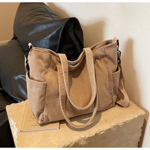Detailed side view of khaki corduroy tote bag showing metal hooks and storage pocket