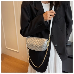 Detail of silver chevron quilted crossbody bag with gold chain strap on model