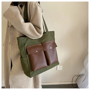 Detail of army green canvas tote bag with brown faux leather pockets and metal snaps