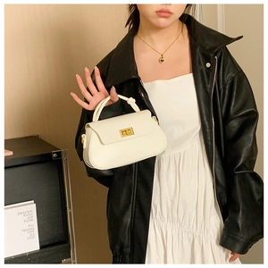 Detail of white PU leather crossbody bag featuring gold metal clasp and a knot handle