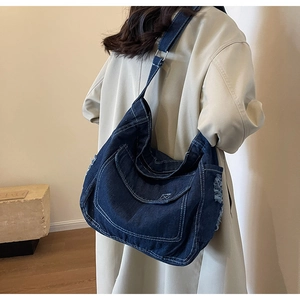 Dettaglio della borsa a tracolla in denim con cuciture bianche e bordi sfrangiati