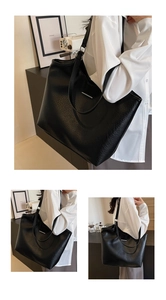 Detailed macro view of black pebbled leather texture and silver metal trim on tote bag