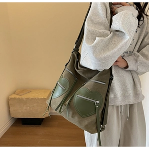 Detail of army green corduroy backpack with large heart-shaped pockets and fringe tassels