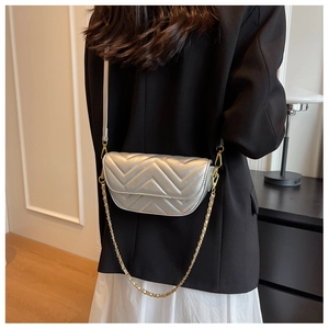 Silver quilted crossbody bag with metal chain strap shown on a black suit jacket