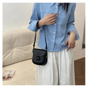 Detail of minimalist black crossbody bag with pleated accordion texture and slim strap