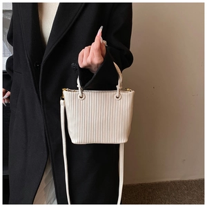 Close-up of cream vertical pleats texture and gold hardware on a bucket bag