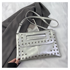 Dettaglio di borsa a busta argento metallizzato con borchie quadrate e texture in pelle